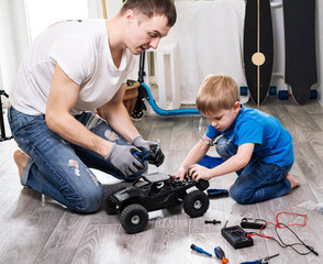 Family time: dad and son little boy repairing a model radio-controlled car at home.