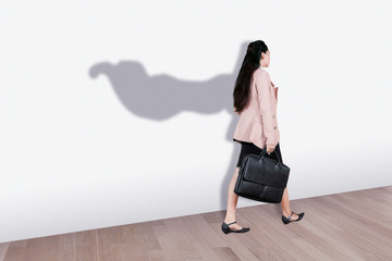 Young business woman with superhero cape shadow