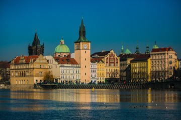 Naklejka premium Prague, Czech Republic / Europe - February 16 2019: View of Novotneho footbridge and historical buildings, reflection in Moldau river, bright sunny cold day, blue sky, seagulls and ducks on water