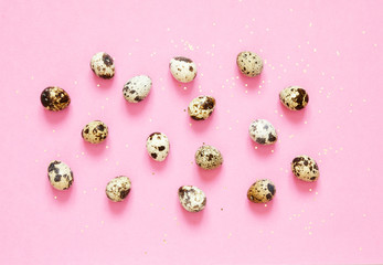 Pattern with quail eggs and golden glitter on pink background.