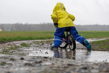 child riding a balance bicycle in rain