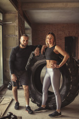Fototapeta na wymiar Healthy active couple of diverse caucasian sportspeople looking at camera while training in crossfit workout in gym. Sport and healthy lifestyle motivation.