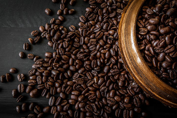 Fresh roasted arabica and robusta coffee beans. Coffee in a wooden bowl on a dark wood background