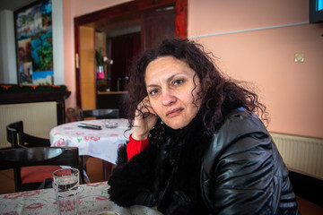 Young woman sitting in the restaurant and drink coffee. Old rustic restaurant on mountain near the road.