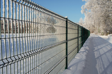 The metal fence in the winter Park is depicted in a sharp perspective, occupies half of the image field, close-up.