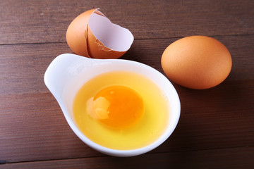 egg yolk in a white bowl and raw egg on the table. ingredients for cooking. concept. View from above.