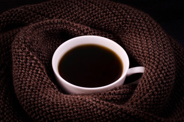 Obraz na płótnie Canvas Black coffee in a white cup with a brown scarf. Winter comfort
