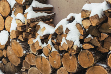 Chopped stock of firewood under snow on the street. Firewood for fireplace and bbq