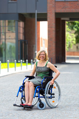 Obraz na płótnie Canvas young adult woman on wheelchair on the street