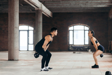 two athletes training with kettlebells. side vuiew full length photo. health care, wellness