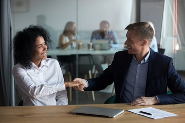 Happy diverse millennial workers starting meeting with handshaking