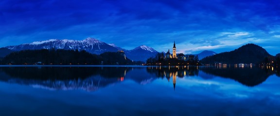 Beautiful view of famous Bled Island (Blejski otok) at scenic Lake Bled with Bled Castle (Blejski grad) and Julian Alps in the background in golden morning light at sunrise in summer, Slovenia 