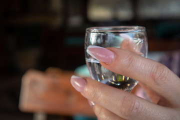 Women's hands holds small glass of alcohol drink in restaurant