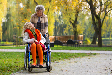 young woman on wheelchair with old woman in the park
