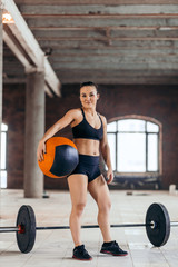 Fototapeta na wymiar happy slim fit girl with a medicine ball looking at the camera in the sport center, restm relaxation, break , full length photo