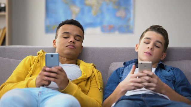 African-American and Caucasian teens scrolling smartphones, having leisure time