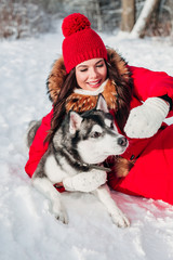 Young woman playing with her Husky dog in winter park