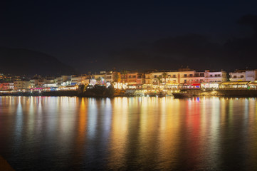 Night view of Hersonissos. Reflection of city lighting in the water.