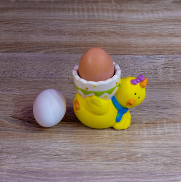 Dark and white egg on the table and egg stand in the form of chicken