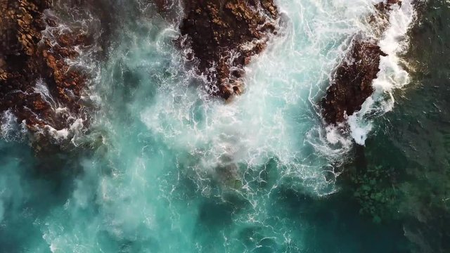 Top view vertical position of big waves going on the rocks at the beach - coast landscape from above with ocean water and rocky coast - outdoor nature dangerous and beautiful concept