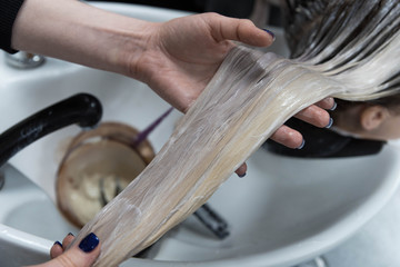 Beauty concept - Professional hairdresser applying shampoo, washes color paint off and massaging hair of a customer. Woman having her hair washed in a hairdressing beauty salon