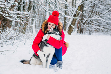 Fototapeta na wymiar Woman caresses the Husky dog in winter forest