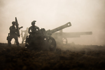 Fototapeta na wymiar Battle scene. Silhouette of old field gun standing at field ready to fire. With colorful dark foggy background. Selective focus