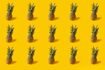 Fototapeta premium Summer colorful fruit minimal pattern of fresh pineapples on yellow background with shadow