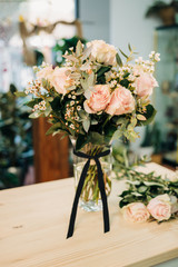 Pink Roses bouquet in a vase on a wooden table. Florist