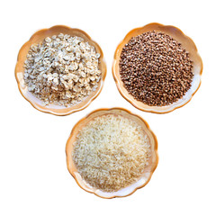 Polished rice, buckwheat and oatmeal are in saucers. Isolated on a white background.