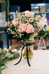 Pink Roses bouquet in a vase on a wooden table. Florist