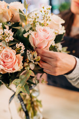 Obraz na płótnie Canvas Woman florist makes a pink roses bouquet on wooden table