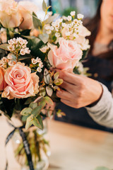 Woman florist makes a pink roses bouquet on wooden table © ManuPadilla