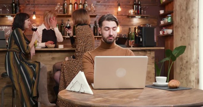 Man enjoying a cup of coffee during an online conversation; Young handsome man engaged in a skype conversation while enjoying a coffe in a coffee shop