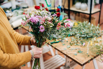 Man florist makes flowers bouquet  and wrapping in pack paper