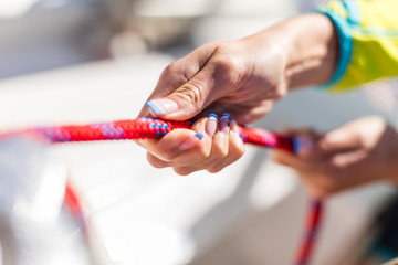 Holder of rope on sailboat, woman pulling rope