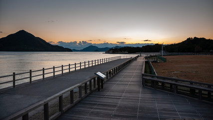 Beautiful sunset scene seen on the island of Okunoshima, also known as the "Bunny Island", which is a small island located in the Inland Sea of Japan, with boardwalks and dramatic clouds in the sky.