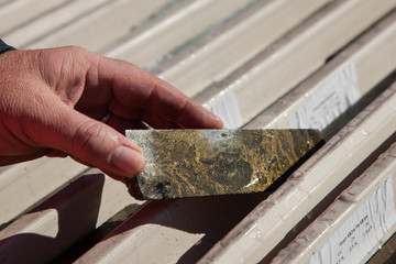 Hand holding a core sample containing copper deposits