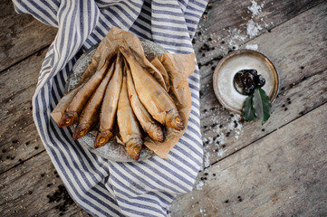 Golden smoke-dried fish on plate on a baking paper on the grey striped napkin