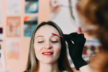 Master black gloves makes the makeup combing the eyebrows after the procedure, laminating and microbleeding