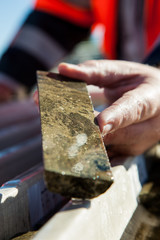 Hand holding a core sample containing copper deposits