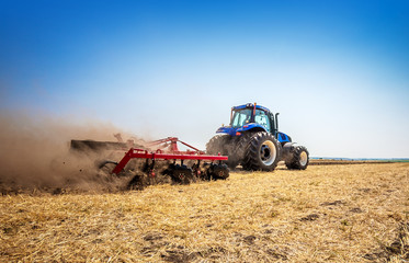 The tractor plows the field, cultivates the soil for sowing grain. The concept of agriculture.