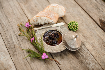 Composition of the cones jam in the silver plate with a cap, tree branch and bread near it