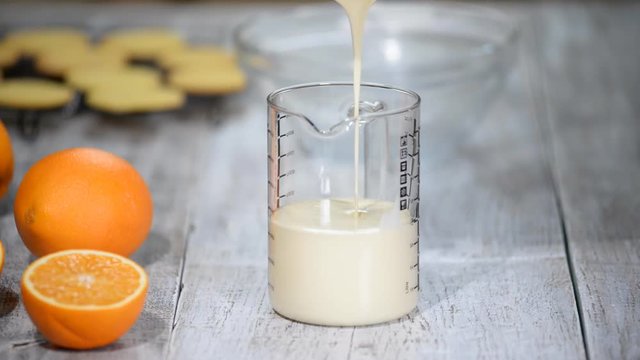 Woman Pours Vanilla Mousse Into Glass Measuring Cup.
