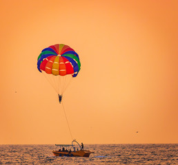 Parasailing on Baga Beach, Goa  in summer. person under parachute hanging mid air. Having fun. Tropical Paradise. Positive human emotions, feelings, family, travel, vacation.