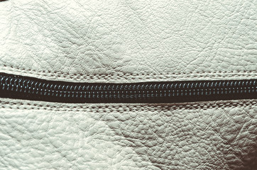 white leather with a lock, part of the zipper, leather background