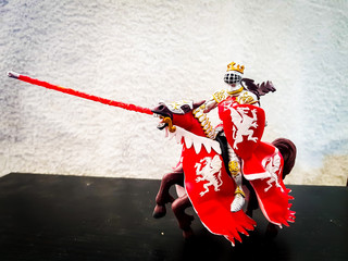 Toy figure of medieval knight riding a horse with shield and colorful uniform war battle