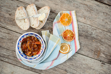 View from above on the beautiful ornate plate with a delicious orange jam on the napkin with dried oranges near the bread