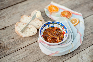 View from above on the blue ornate plate with a delicious orange jam on the napkin with dried oranges near the bread