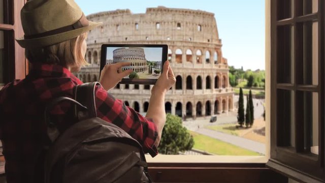 tourist takes photo of roman colosseum,traveler woman photographs rome city using tablet high view